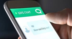Close-up of a smartphone showing a live chat window with the greeting “Hi! How can I help you?”