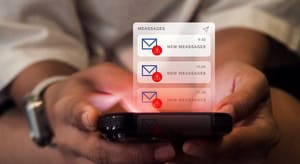 person holding a smartphone as a stack of new message notifications with red alert icons floats above the screen.